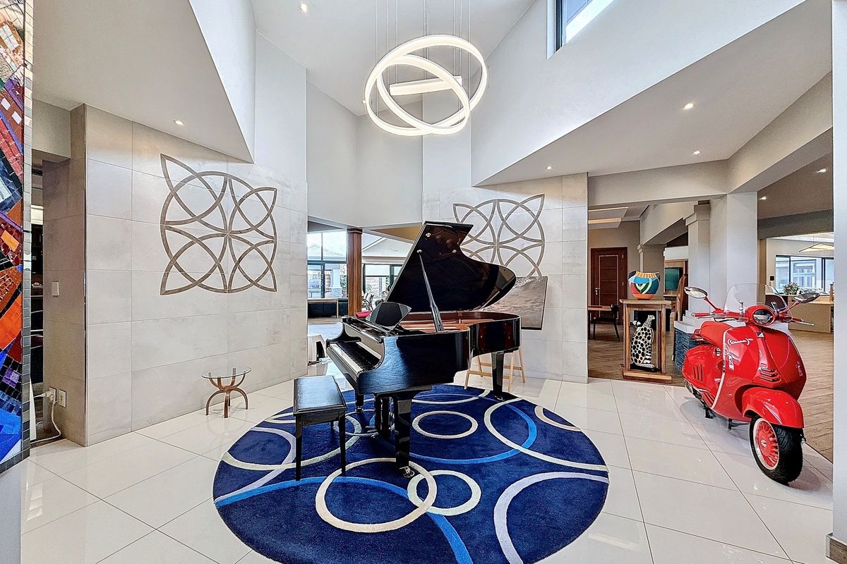 Spacious living area featuring high vaulted ceilings, modern recessed and pendant lighting, and polished tiled flooring with decorative wall accents.