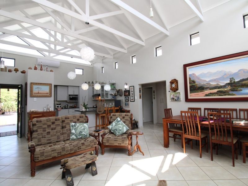 Spacious open-plan living and dining area featuring high vaulted ceilings with exposed trusses, tiled flooring, and a modern kitchen with built-in cabinetry.