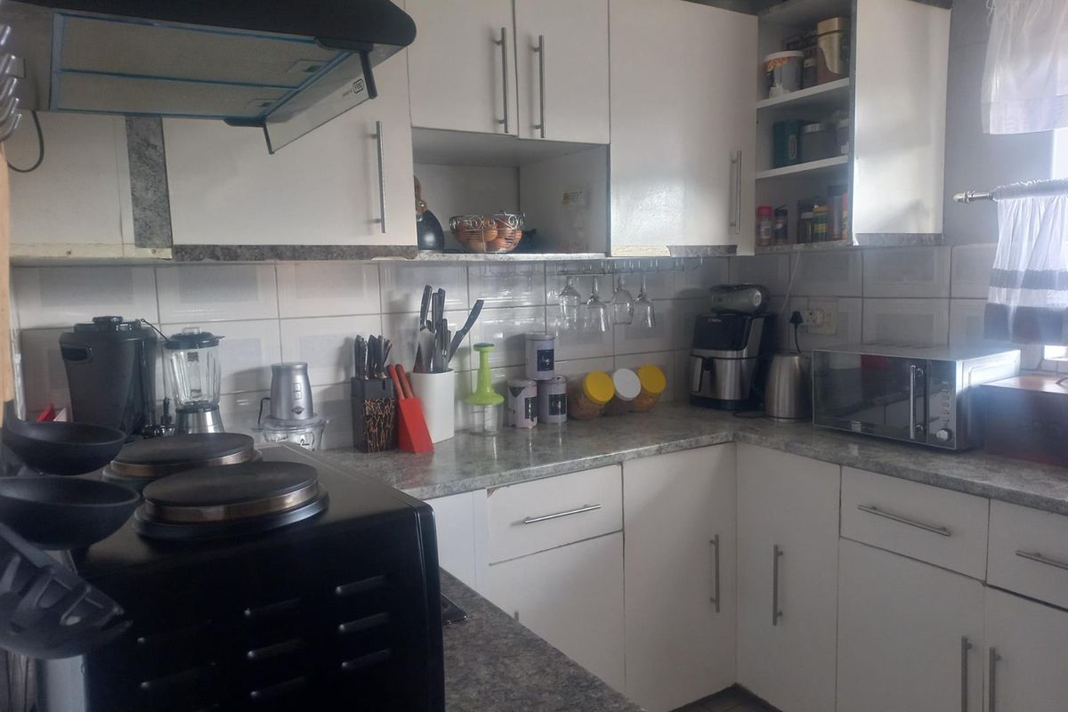 A functional kitchen featuring white cabinetry, laminate countertops, a tiled backsplash, and a built-in extractor fan.