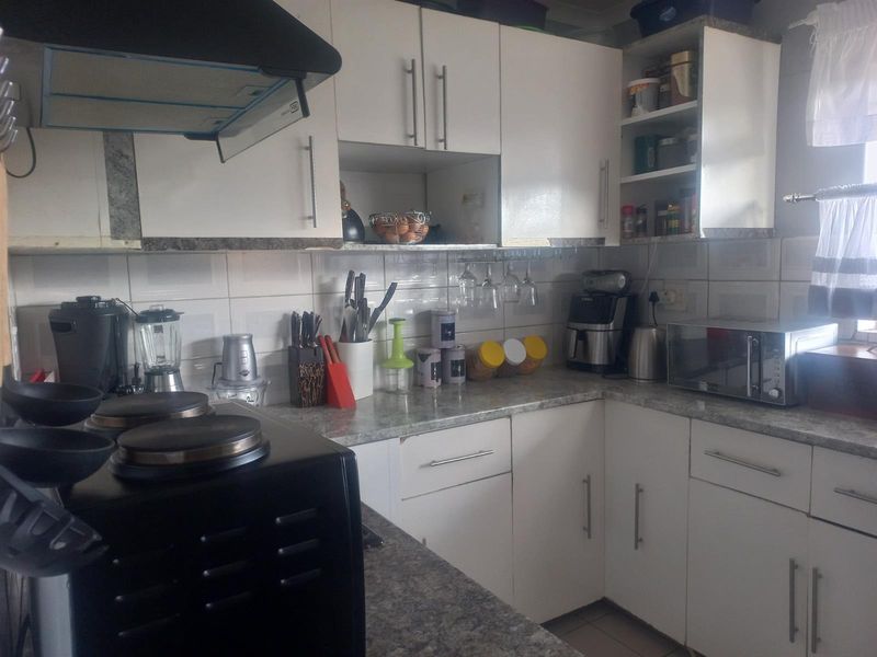 A functional kitchen featuring white cabinetry, laminate countertops, a tiled backsplash, and a built-in extractor fan.