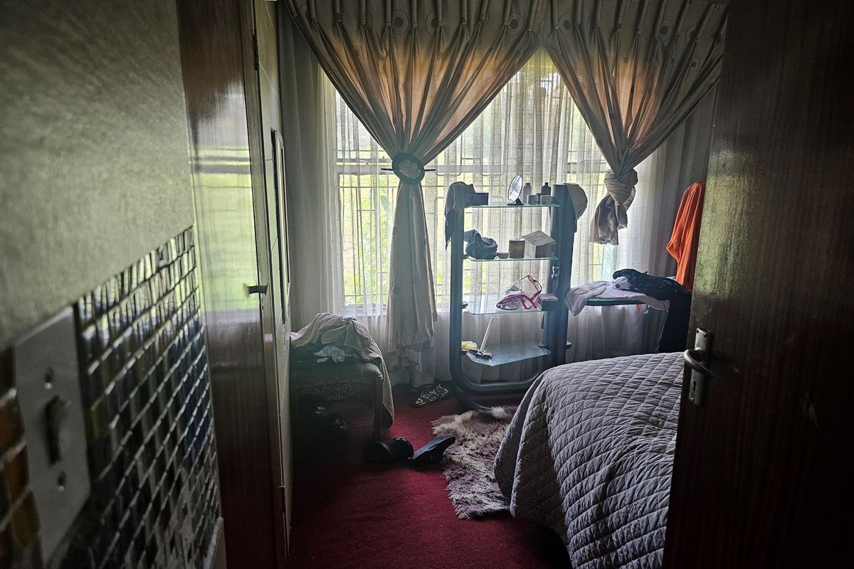 A bedroom featuring carpeted flooring, a window with curtains, and built-in cupboard storage.