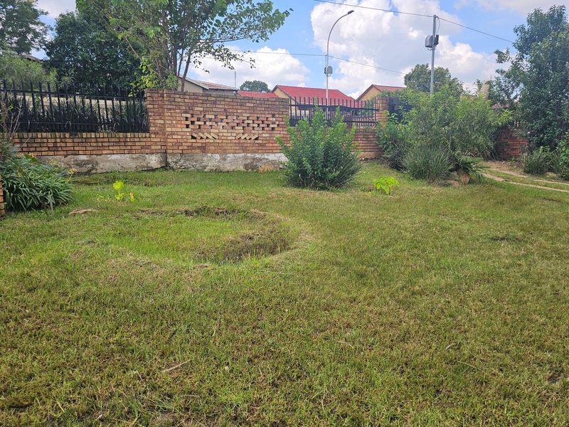A private garden area featuring a brick boundary wall with integrated metal security fencing and an established lawn.
