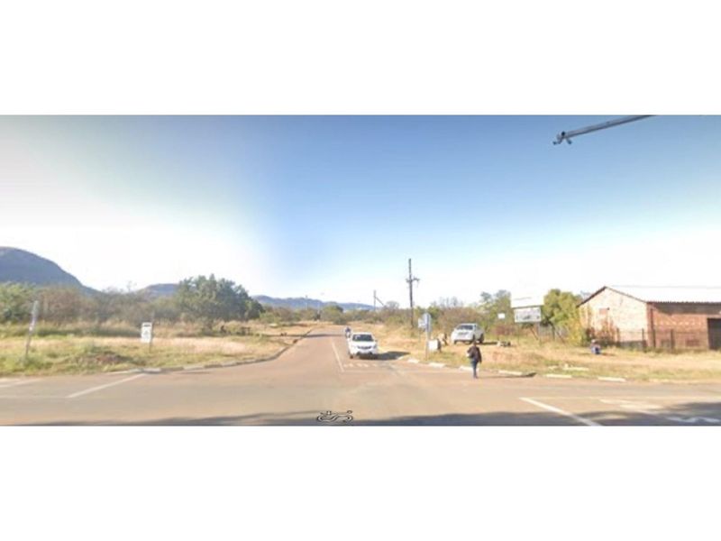 A street-level view of the access road leading to the residential land, featuring surrounding natural landscape and utility infrastructure.