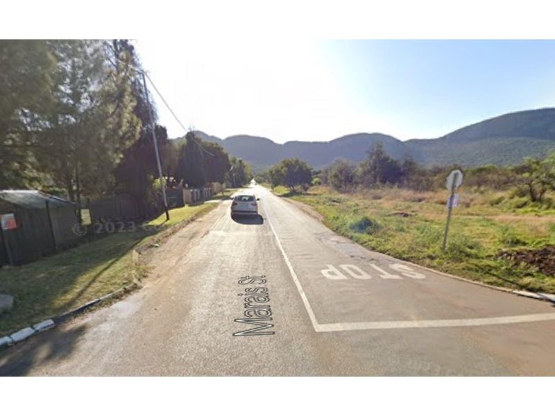 A street view showing the approach to the property location with surrounding landscape and mountain views.
