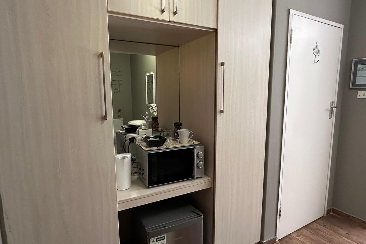 A functional built-in kitchenette or refreshment station featuring light wood cabinetry, a microwave nook, and integrated storage space.