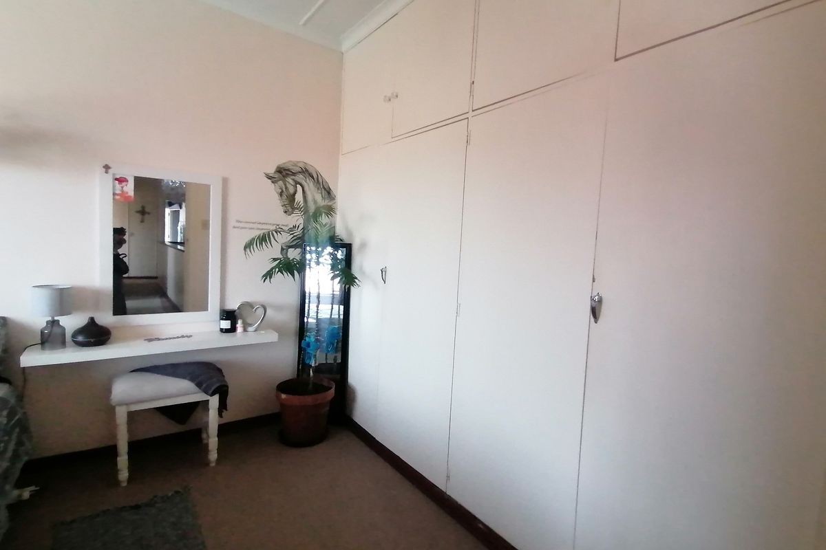 Bedroom featuring extensive floor-to-ceiling built-in cupboards and a wall-mounted vanity shelf.