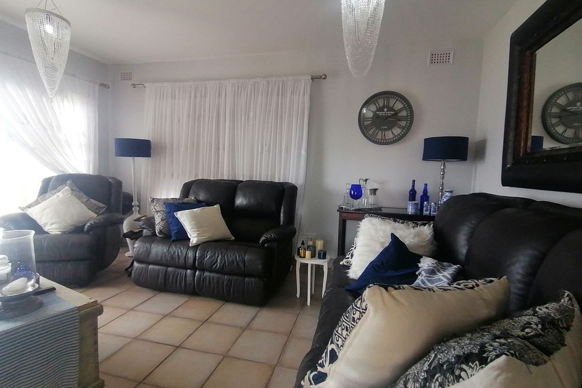 A comfortable living room featuring tiled flooring and large windows with curtains, providing a bright and functional space for relaxation.