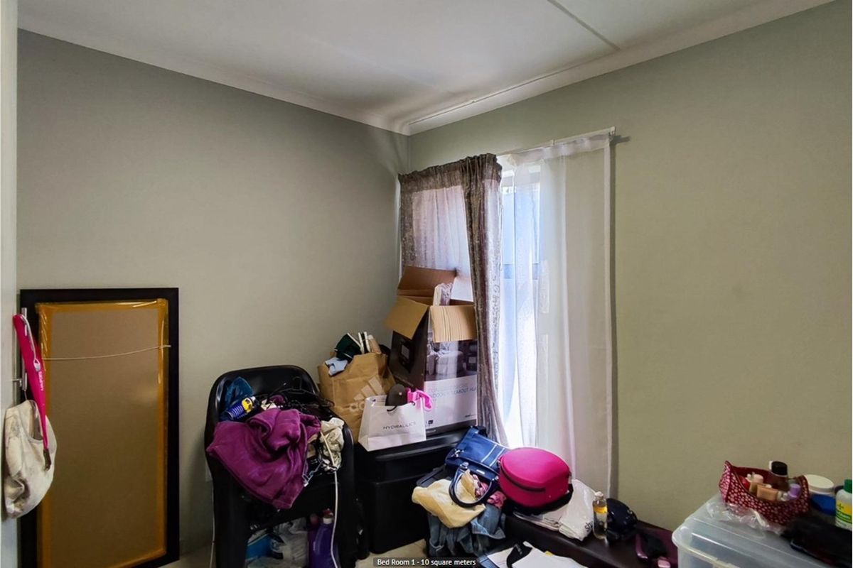 A compact bedroom featuring neutral wall paint and a window with curtain tracks, offering a functional space for a single bed or home office.