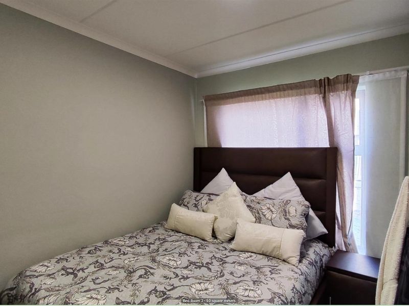 A compact bedroom featuring neutral wall tones, crown molding, and a window with fitted curtain tracks.