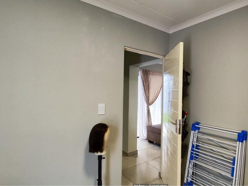 A view from a bedroom looking through a doorway into an adjacent living space with tiled flooring and neutral wall finishes.