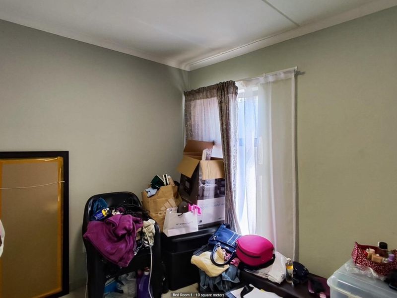 A compact bedroom featuring neutral wall paint and a window with curtain tracks, offering a functional space for a single bed or home office.