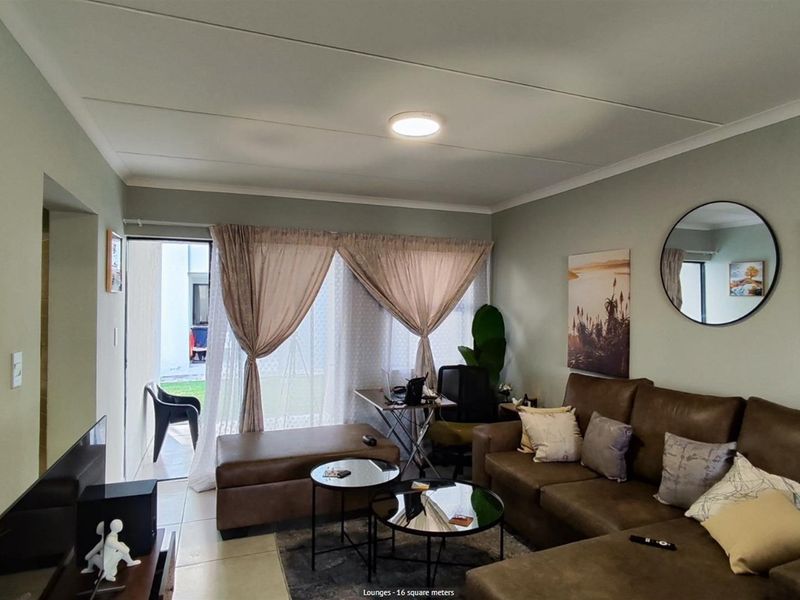 A comfortable living room featuring tiled flooring, a ceiling-mounted light fixture, and sliding glass doors that provide direct access to an outdoor patio area.