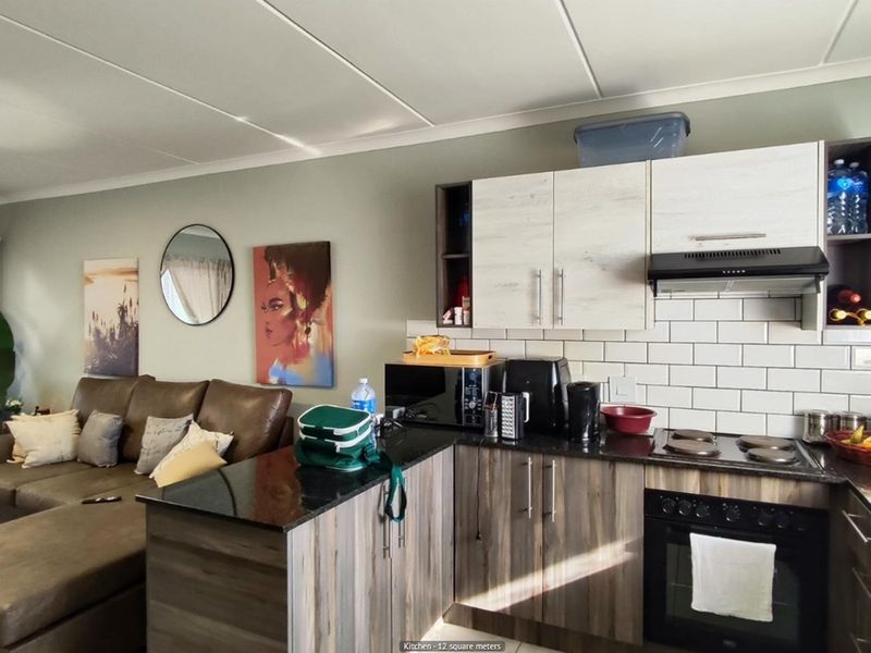 Open-plan kitchen featuring modern cabinetry, granite countertops, subway tile backsplash, and integrated oven with extractor fan, seamlessly flowing into the living area.