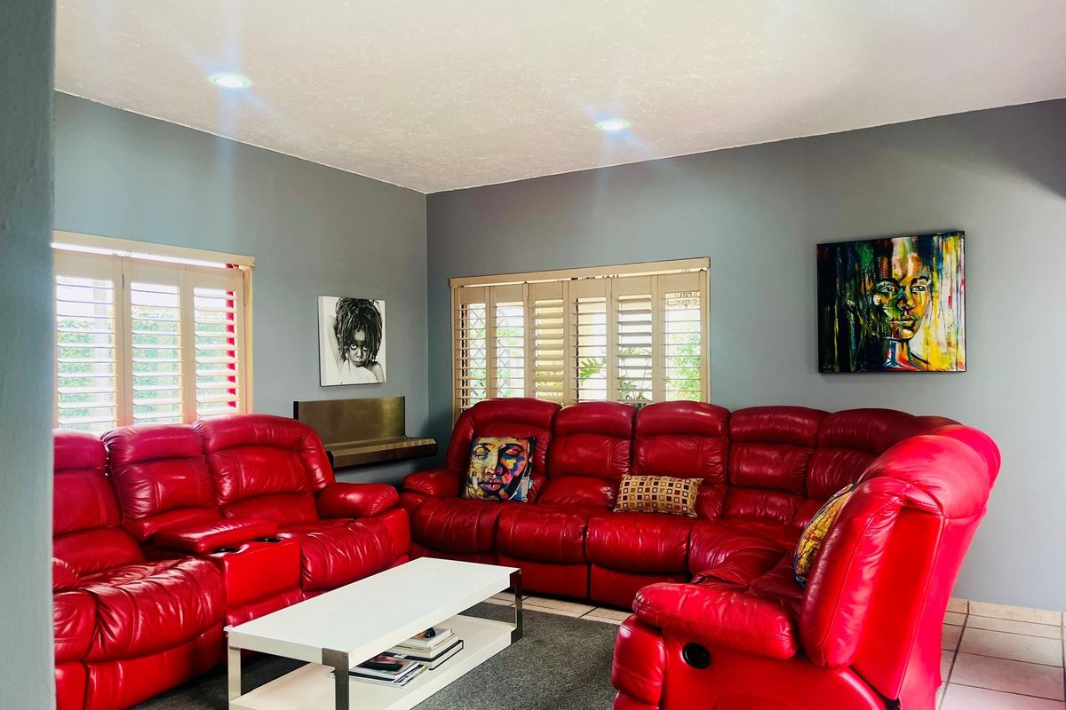 A living room featuring grey walls, recessed ceiling lighting, and plantation shutters on the windows.