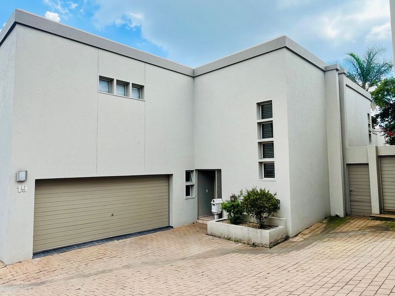 Modern double-storey residential facade featuring a double garage, paved driveway, and minimalist architectural design with clean lines.