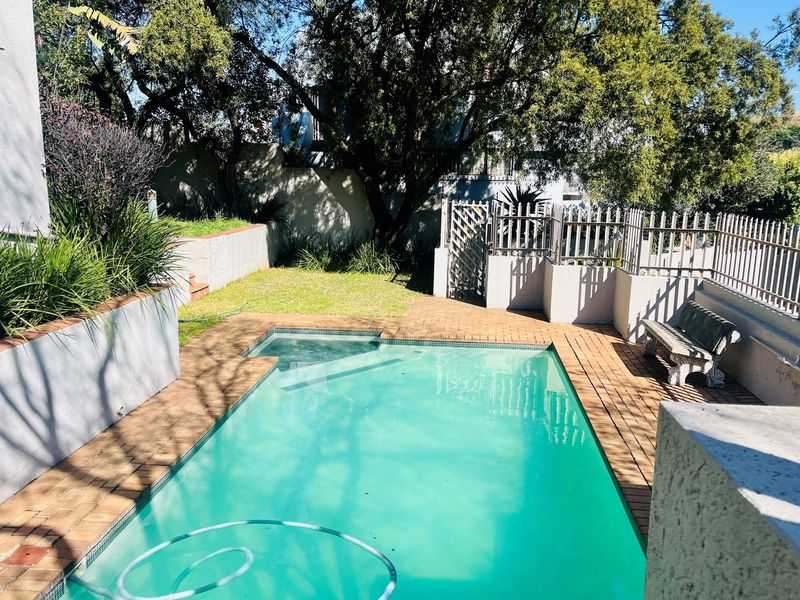 A private outdoor pool area featuring paved decking, a small lawn, and perimeter fencing, providing a functional space for relaxation and recreation.