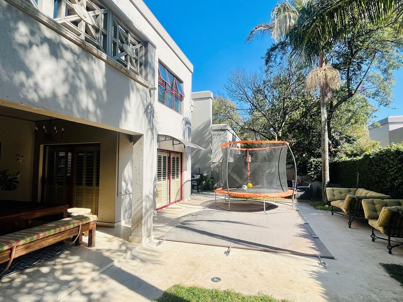 Spacious rear patio area featuring a covered entertainment space, concrete paving, and direct access to the garden.