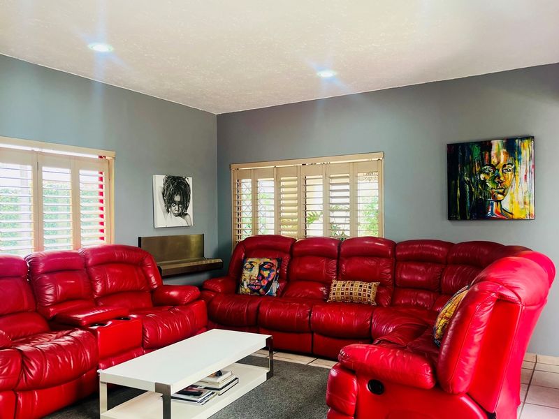 A living room featuring grey walls, recessed ceiling lighting, and plantation shutters on the windows.