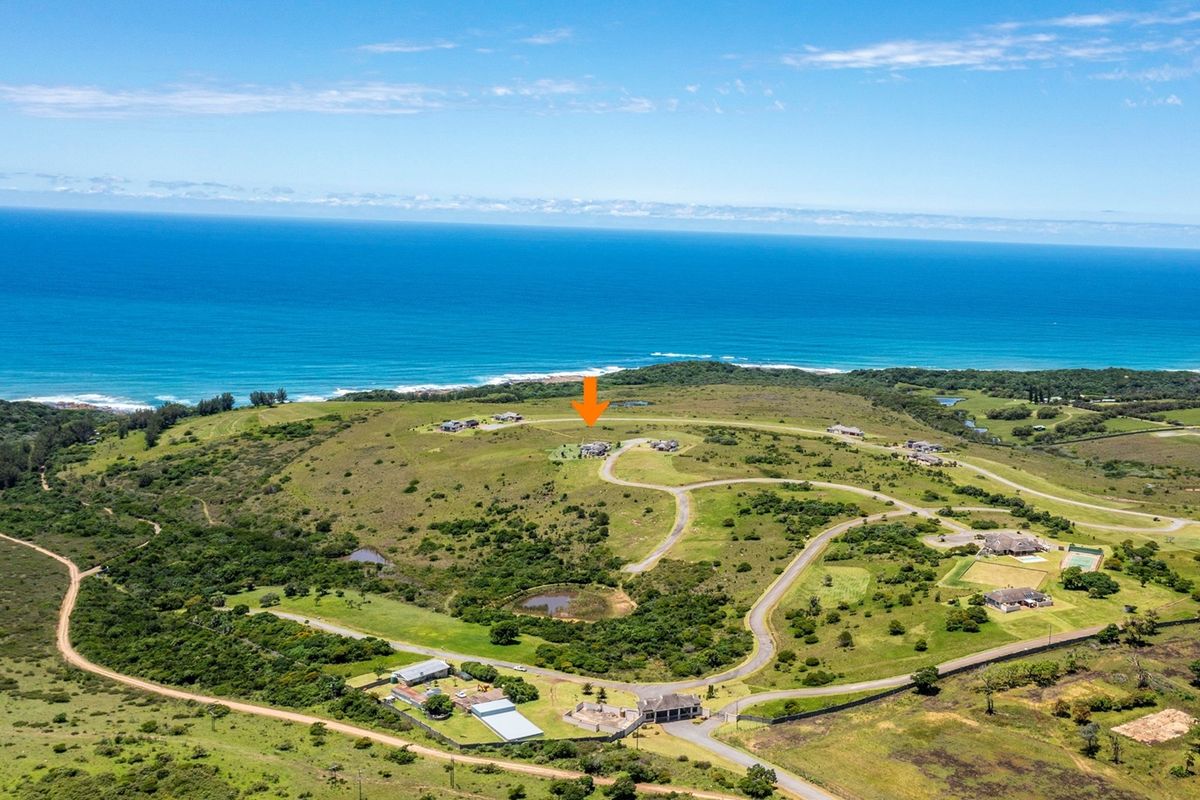 Aerial view of a coastal residential estate featuring expansive green landscapes, internal road networks, and proximity to the ocean.