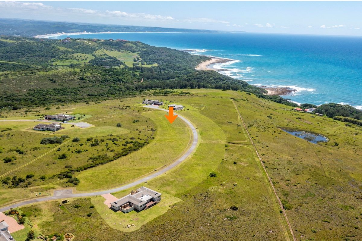 Aerial view of a vacant residential plot in a coastal estate, featuring expansive green landscape and proximity to the ocean.