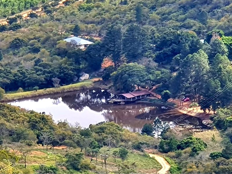 An elevated aerial view of a rural farm property featuring a large dam, surrounding natural vegetation, and a dwelling nestled within the landscape.