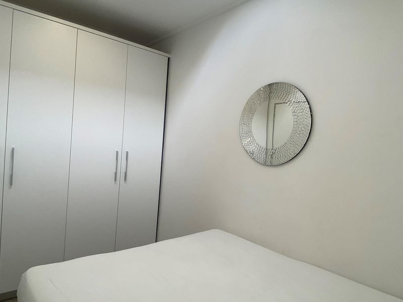 A clean bedroom featuring built-in floor-to-ceiling wardrobes with modern handles, providing ample storage space.