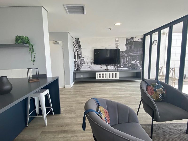 Modern open-plan living area featuring a sleek kitchen island, built-in media console, and large glass sliding doors leading to an outdoor space.