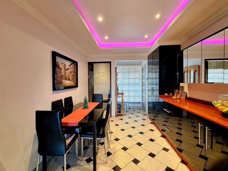 Dining area featuring a tray ceiling with integrated LED lighting, tiled flooring, and built-in high-gloss cabinetry with a countertop.