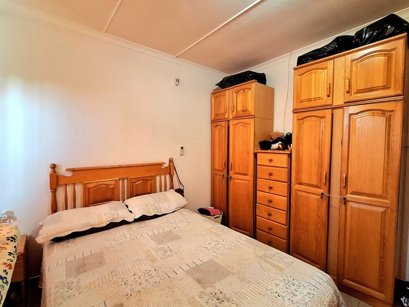 A bedroom featuring built-in wooden cabinetry and tiled flooring, offering functional storage space.