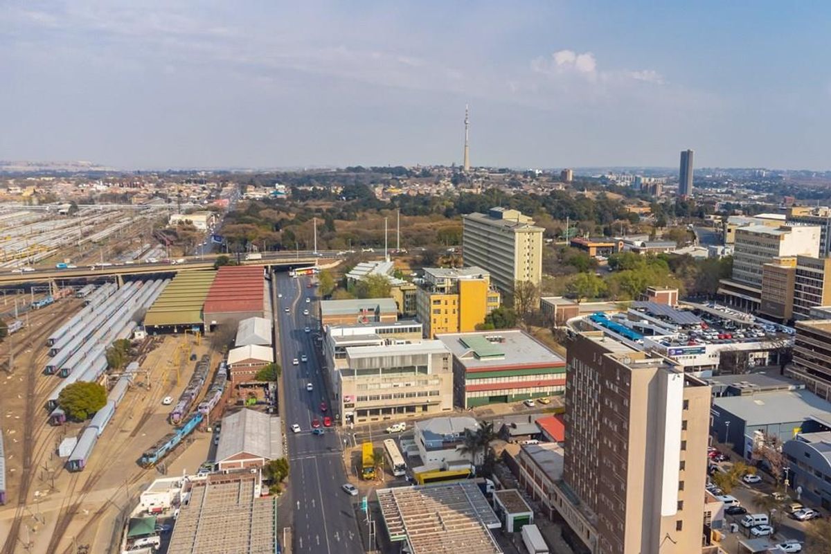 An elevated aerial view of the surrounding urban landscape, featuring nearby transport infrastructure, commercial buildings, and city streets.