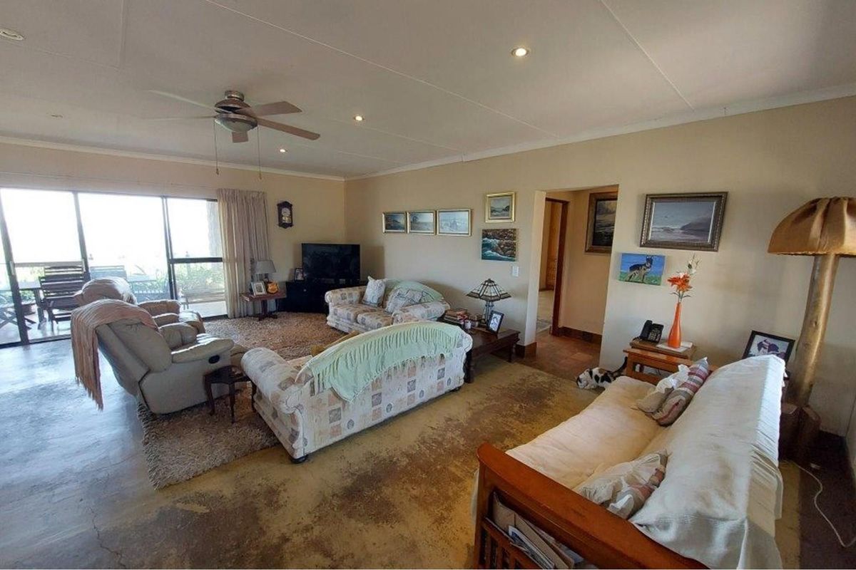 Spacious living room featuring concrete flooring, recessed lighting, a ceiling fan, and large sliding glass doors providing access to the outdoor area.