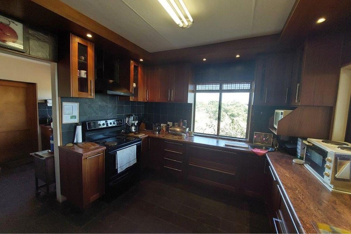 A functional kitchen featuring dark wood cabinetry, stone countertops, a tiled backsplash, and an integrated stove with an extractor fan.