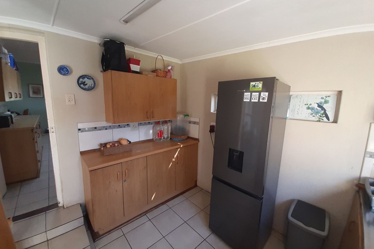 A functional kitchen area featuring wooden cabinetry, tiled flooring, and a tiled backsplash, providing practical storage and workspace.