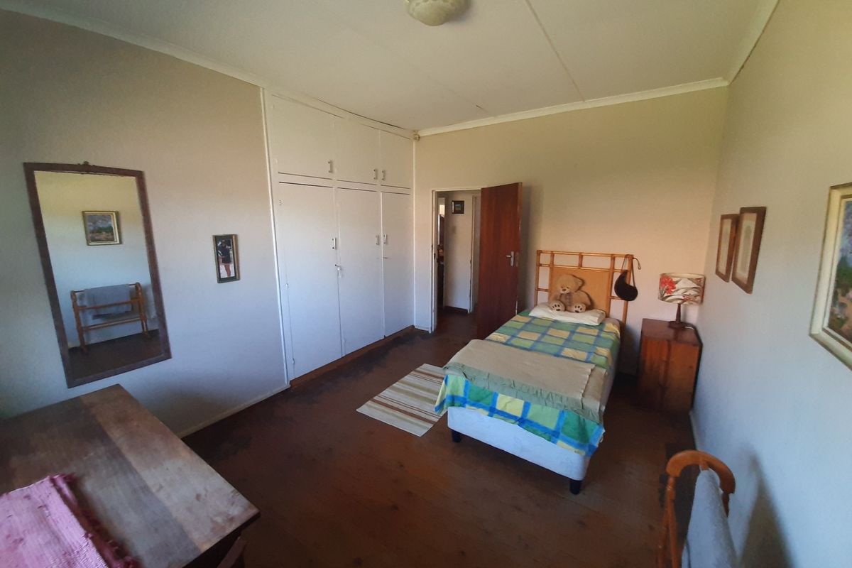 A bedroom featuring built-in cupboards and original timber flooring, offering a functional space with potential for cosmetic updates.