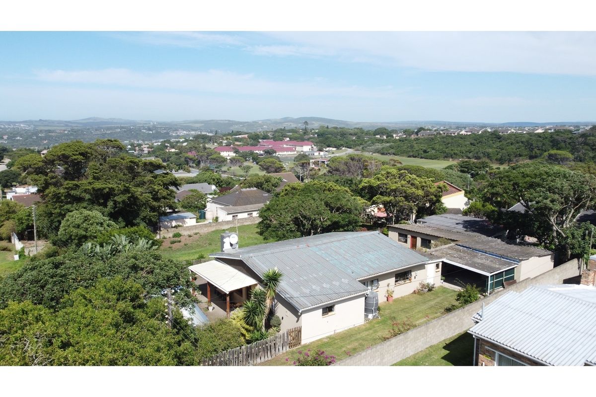 Aerial view of a residential property featuring a metal roof, covered patio, and surrounding garden within a suburban neighborhood setting.