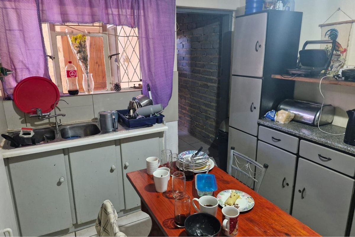 A functional kitchen featuring built-in cabinetry, laminate countertops, and a double bowl sink, requiring cosmetic updates to modernize the space.