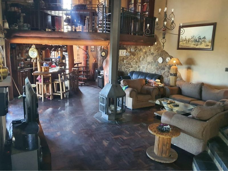 Spacious open-plan living area featuring a central freestanding fireplace, stone feature wall, parquet flooring, and a mezzanine level with a spiral staircase.