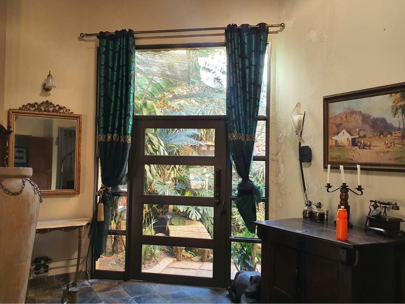 Entrance area featuring slate tile flooring and a timber-framed glass door with garden views, requiring some wall maintenance and cosmetic updates.