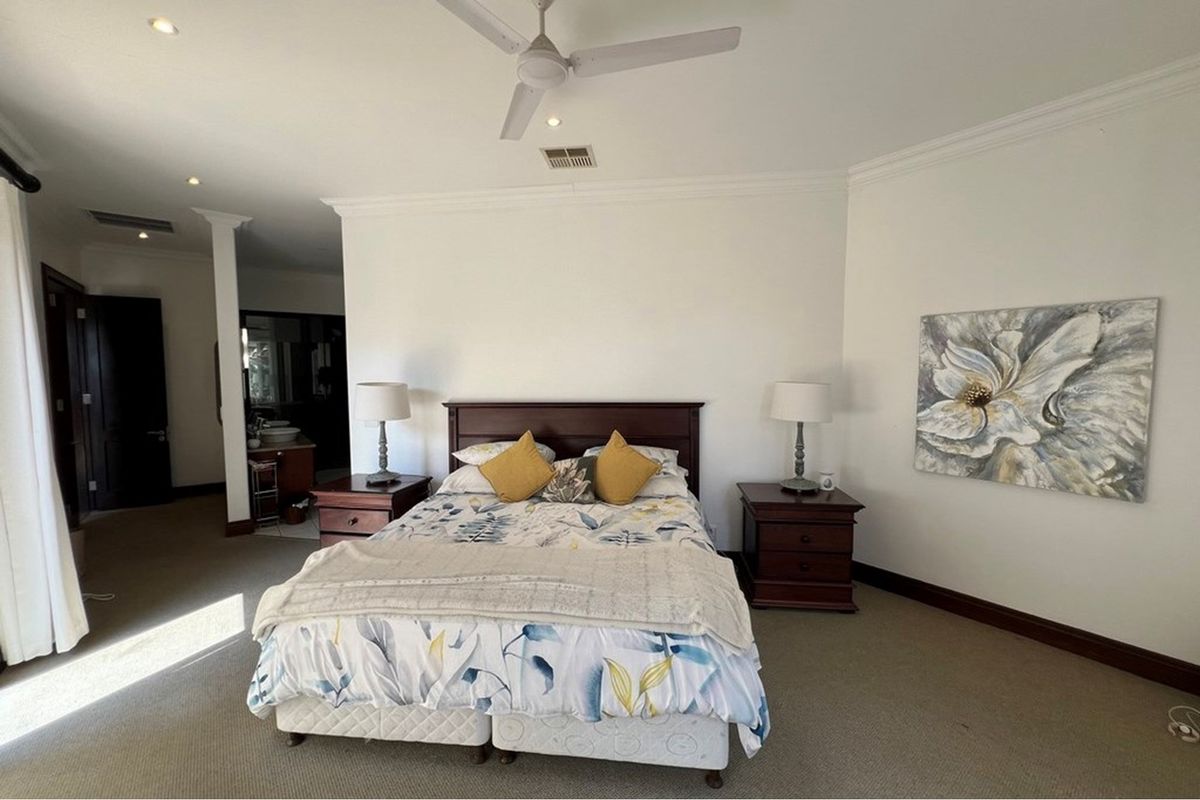 Spacious bedroom featuring neutral carpeting, coved ceilings, recessed lighting, and a ceiling fan, with an adjoining ensuite area visible.
