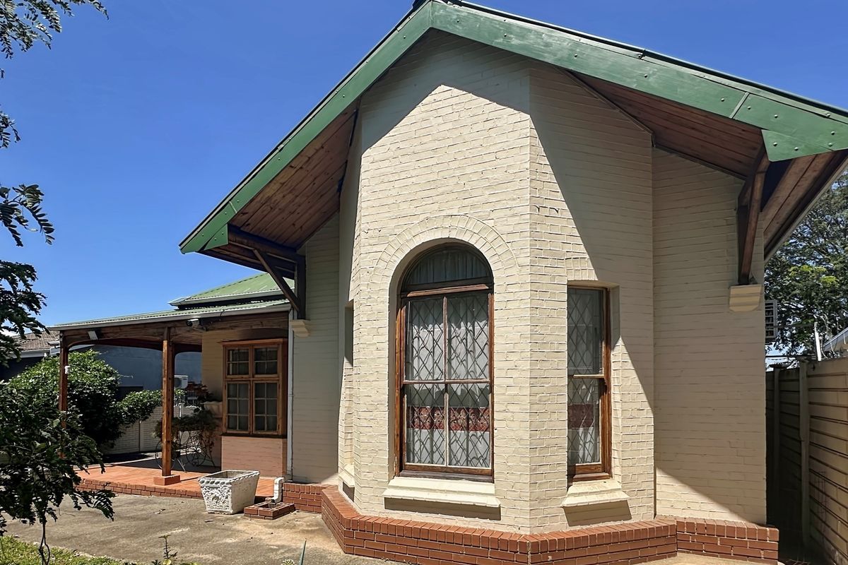 A charming character home featuring a bay window, brick facade, and a covered side patio area with timber detailing.