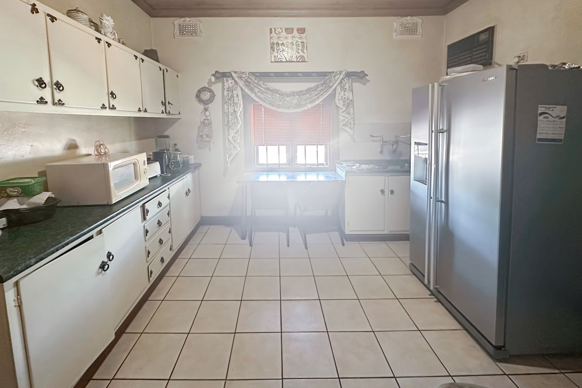 A functional kitchen featuring white cabinetry, tiled flooring, and a window providing natural light, offering a classic layout ready for potential modernization.
