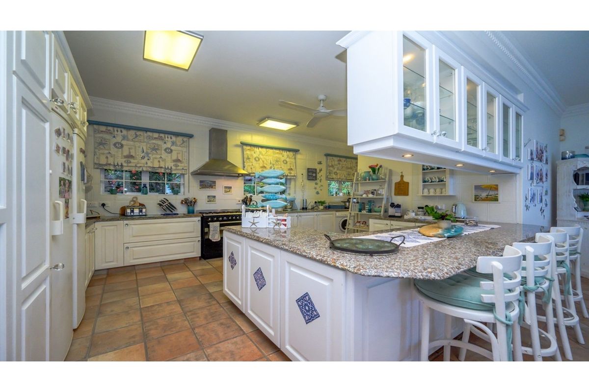 Spacious kitchen featuring a large central island with granite countertops, ample cabinetry, a built-in oven, and a stainless steel extractor fan.