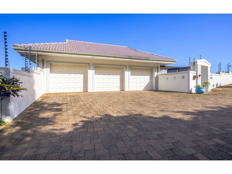 A well-maintained triple garage with paved driveway, secure perimeter walling, and electric fencing.