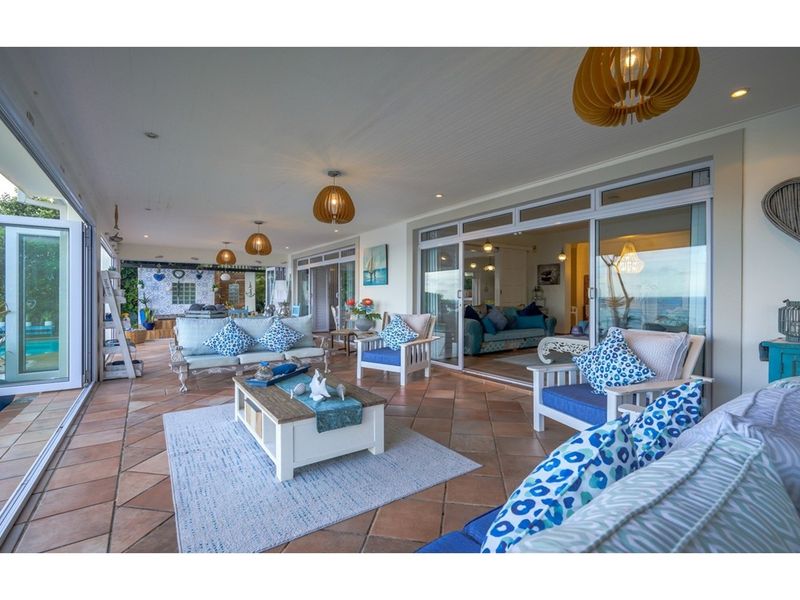 Spacious covered patio featuring terracotta floor tiles, recessed ceiling lighting, and large glass sliding doors providing seamless indoor-outdoor flow.