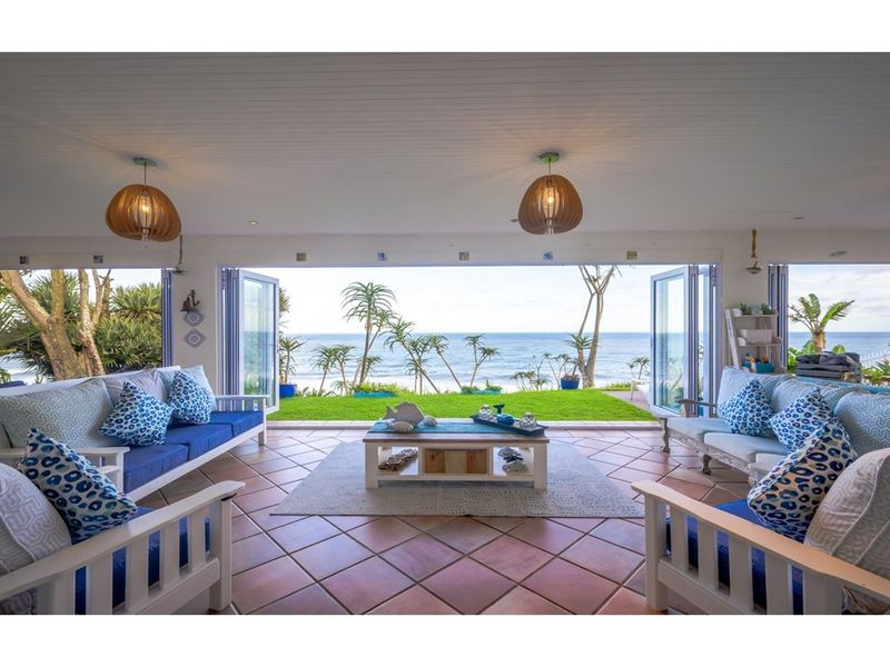 Spacious open-plan living area featuring large bi-fold doors that open onto a lush garden with direct ocean views.
