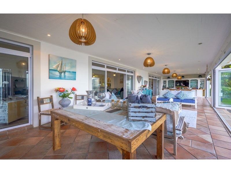 Spacious covered patio featuring terracotta tiled flooring, recessed lighting, and large sliding glass doors providing seamless indoor-outdoor flow.