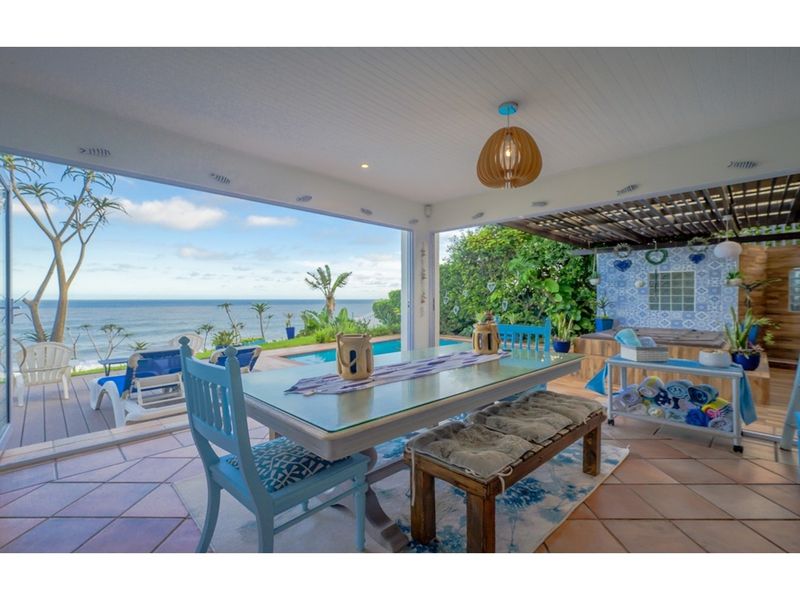 A bright, open-plan patio area featuring tiled flooring, a timber pergola, and seamless indoor-outdoor flow with expansive ocean and pool views.
