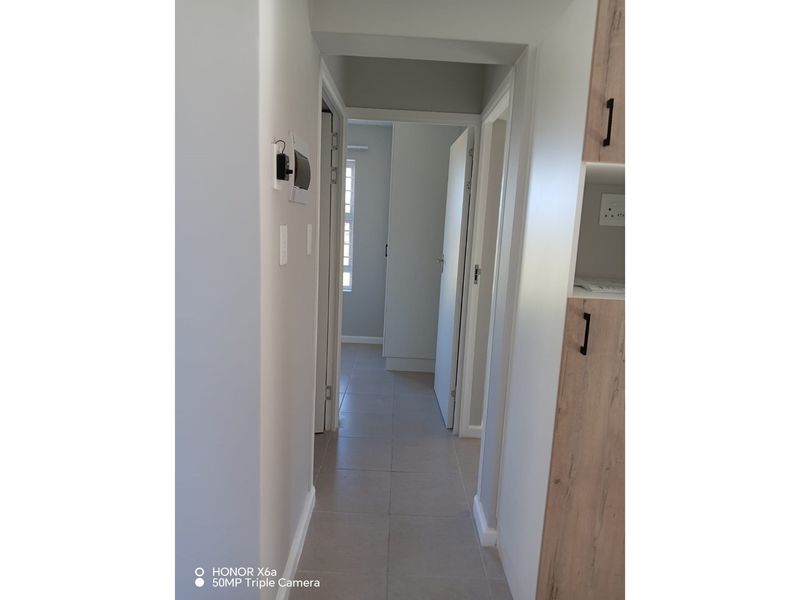 A clean, neutral hallway featuring tiled flooring and built-in cabinetry, providing access to multiple rooms within the townhouse.