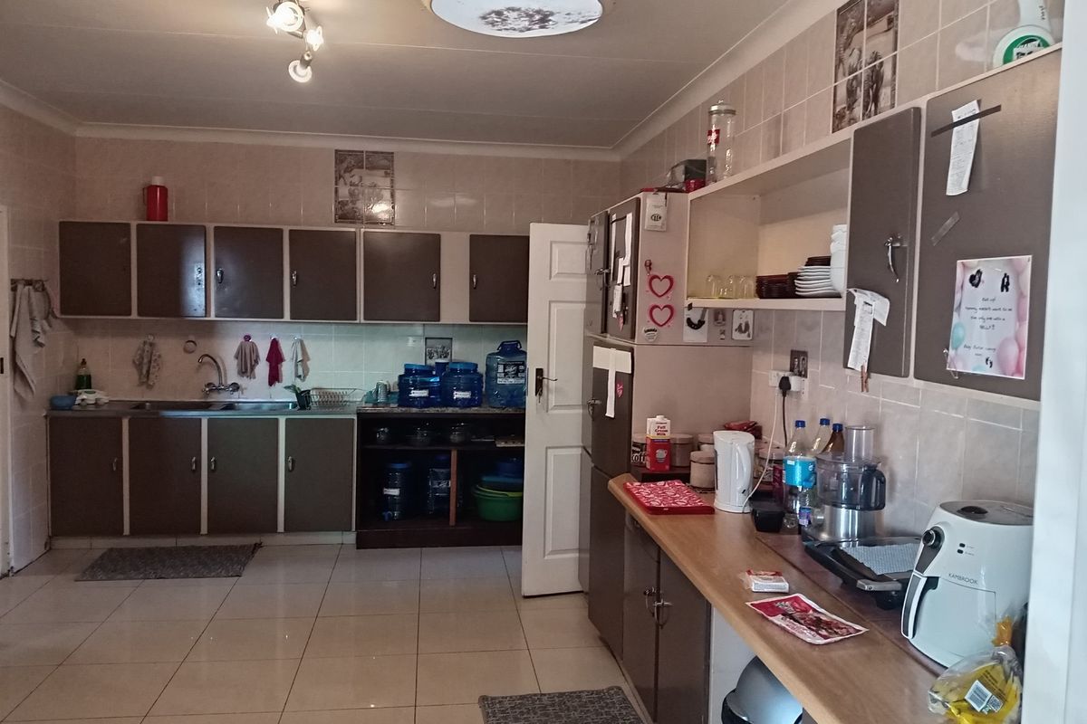 A functional kitchen featuring tiled flooring, ample cabinetry, and a tiled splashback, providing a practical workspace for daily meal preparation.