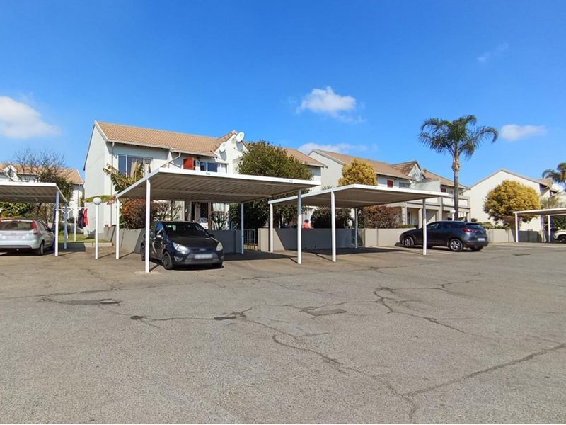 Exterior view of the townhouse complex featuring multiple covered parking carports and a paved driveway area.